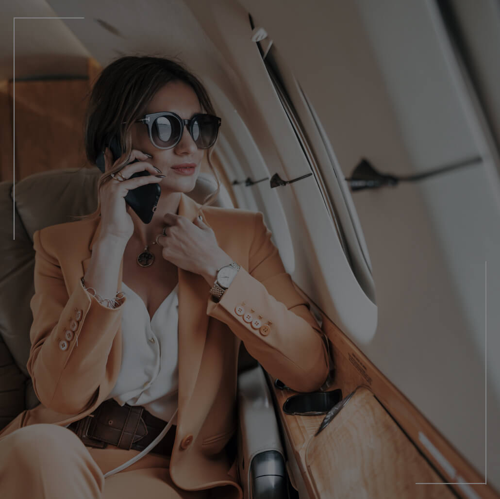 A business woman sits in an airplane while on the phone. 